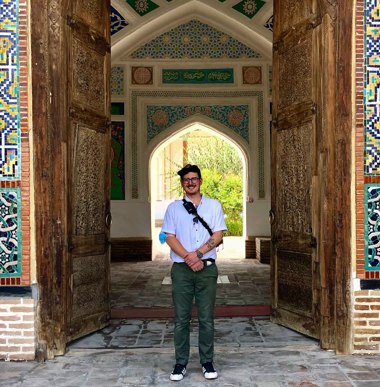 A picture of Matt Brown standing in front of an ornate, large doorway in Central Asia